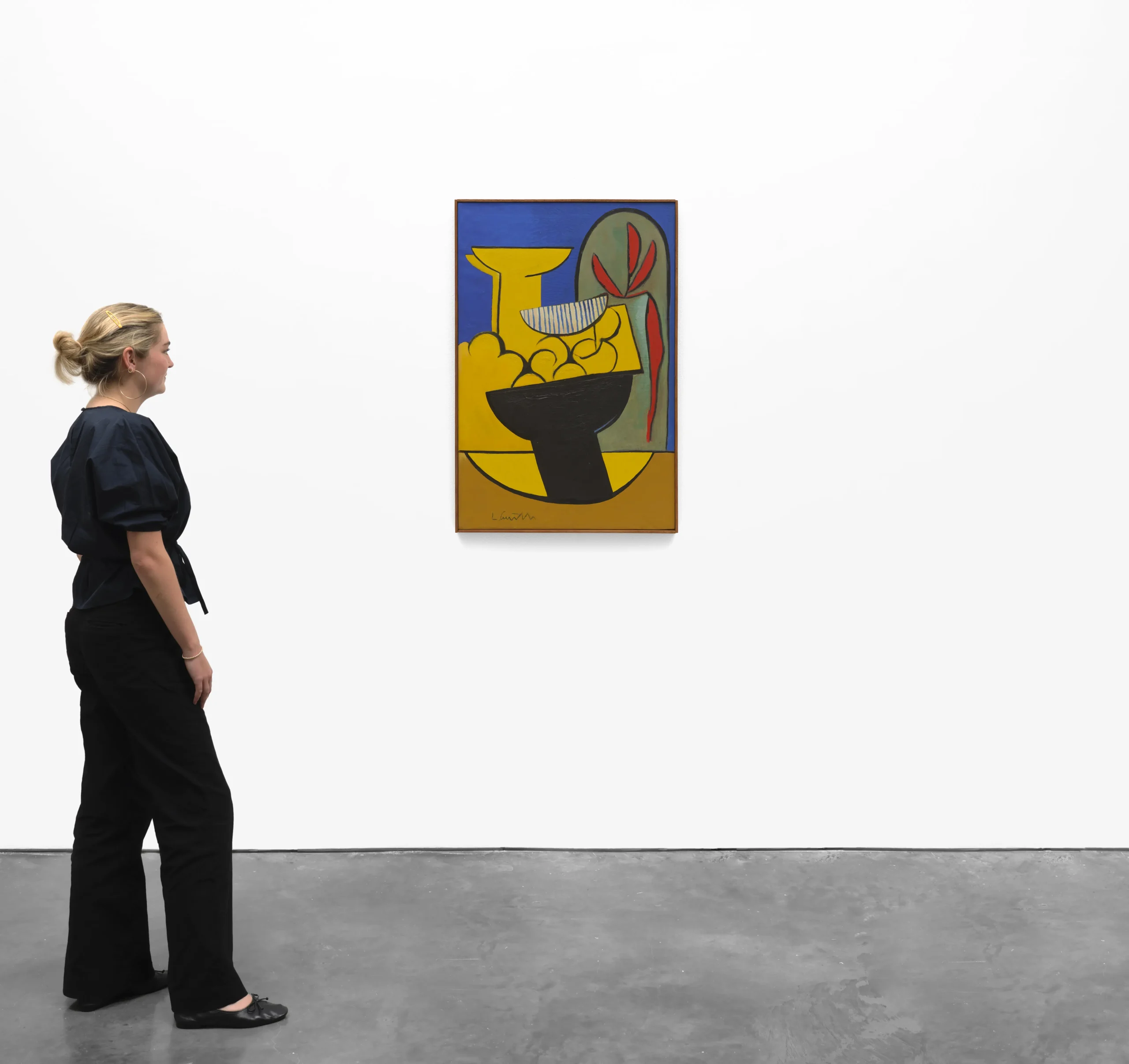 Black Fruit Bowl painting in gallery with woman standing next to painting.